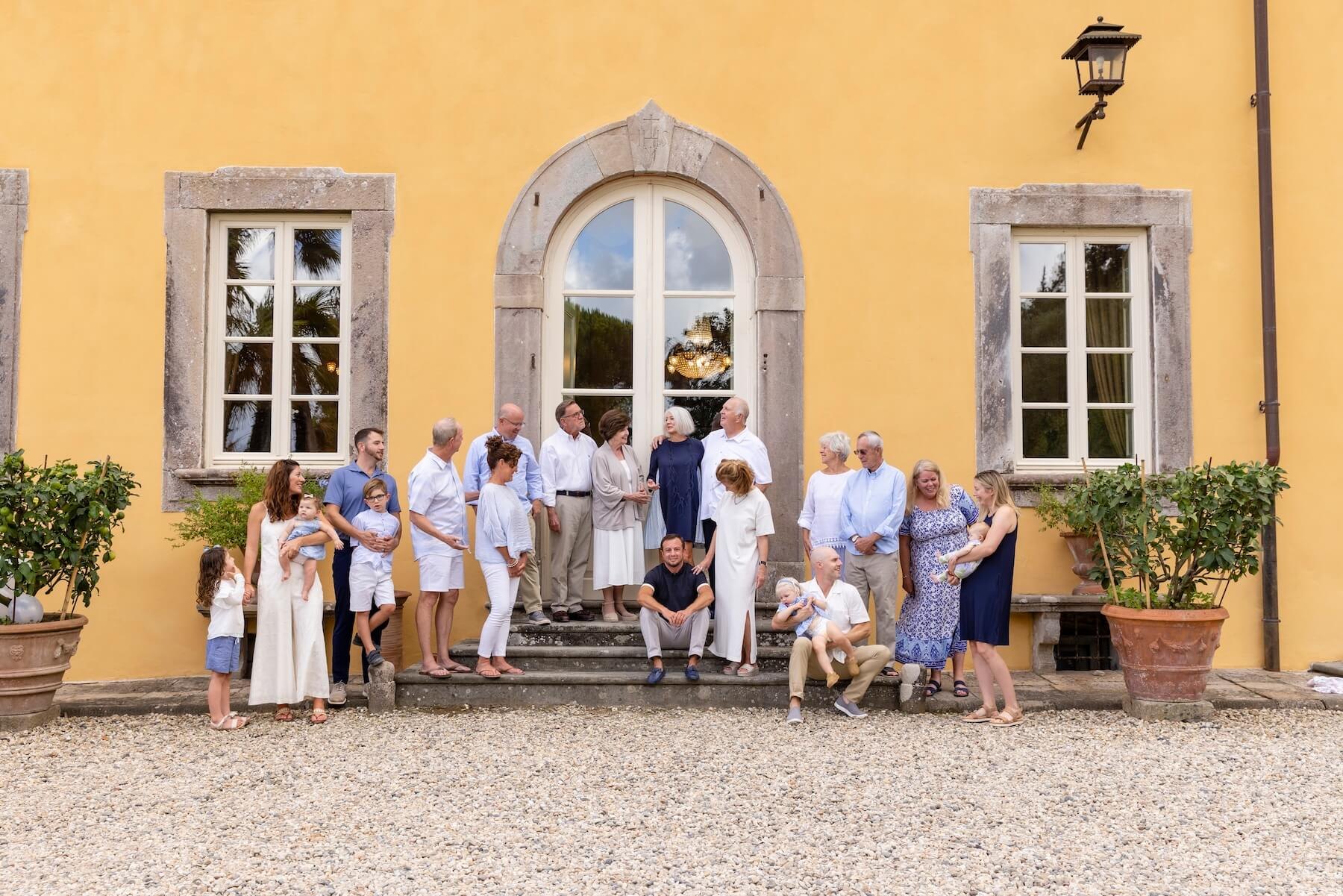 Three generations of a family gathered outside a yellow Tuscan villa